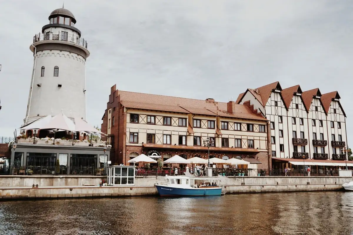 Picturesque waterfront featuring a lighthouse, cafes, and vintage buildings.