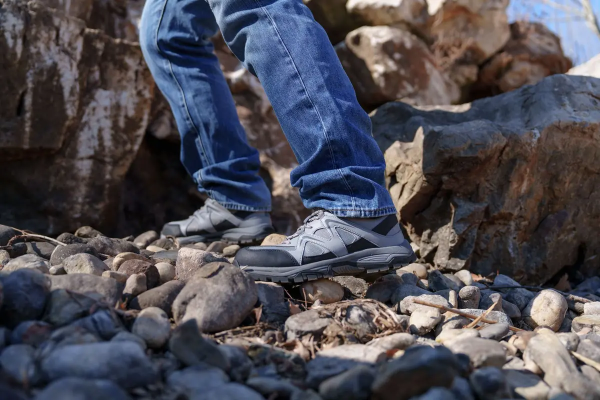 A man in jeans and hiking boots walking over a rocky landscape, perfect for outdoor adventure themes.