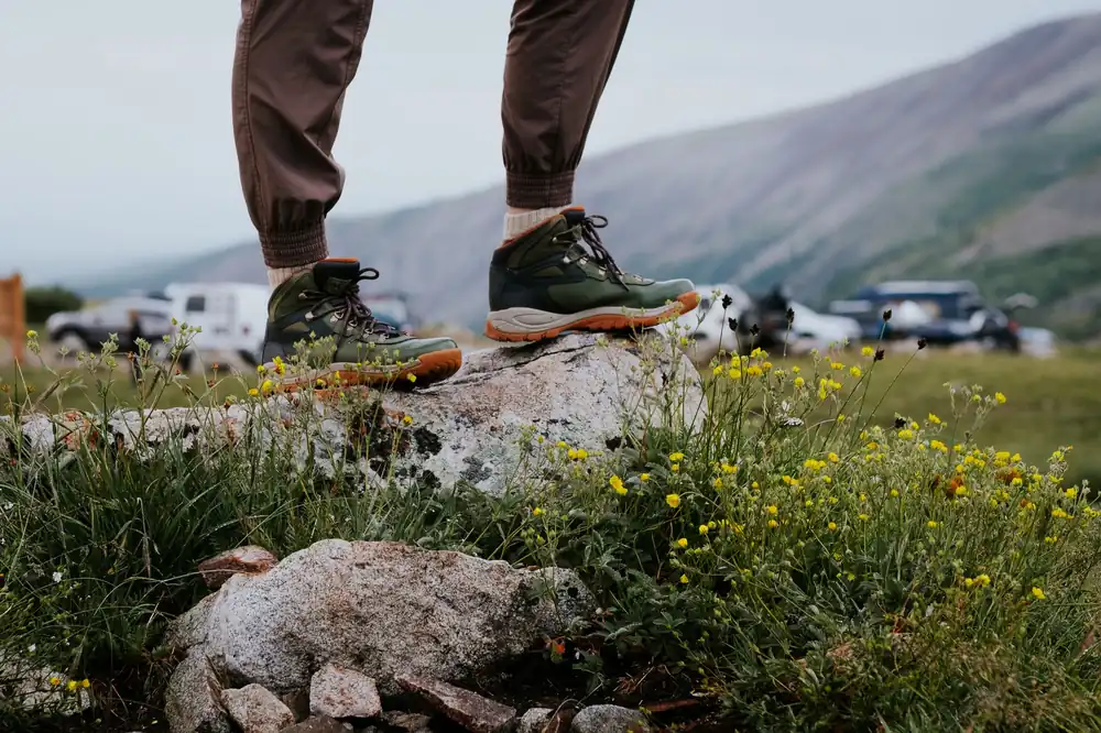 Close-up of hiking boots on a rocky outcrop surrounded by wildflowers in Alma, Colorado.