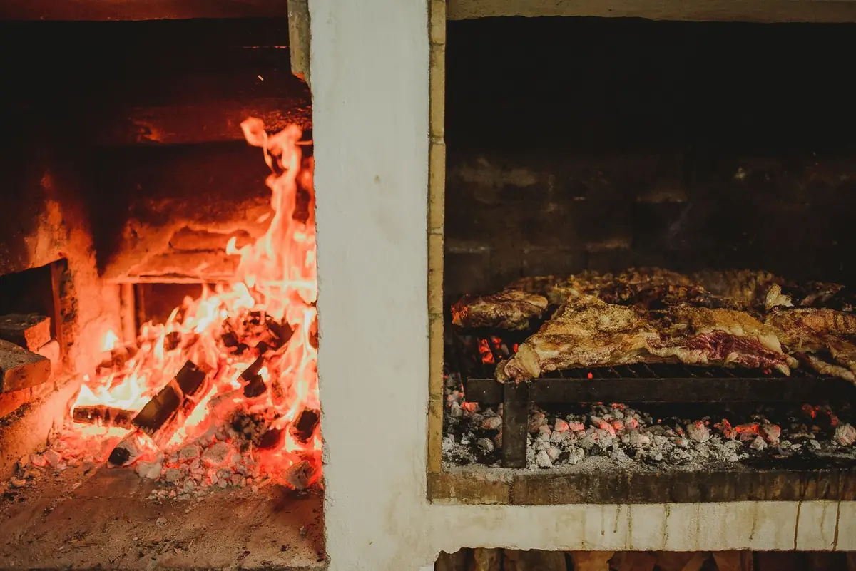 Close-up of meat grilling in a rustic wood-fired oven, creating a warm and cozy atmosphere.