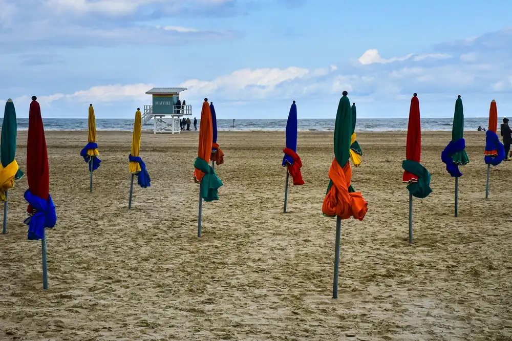 Colorful folded umbrellas on the sandy beach in Deauville, Normandy, France, during summer.