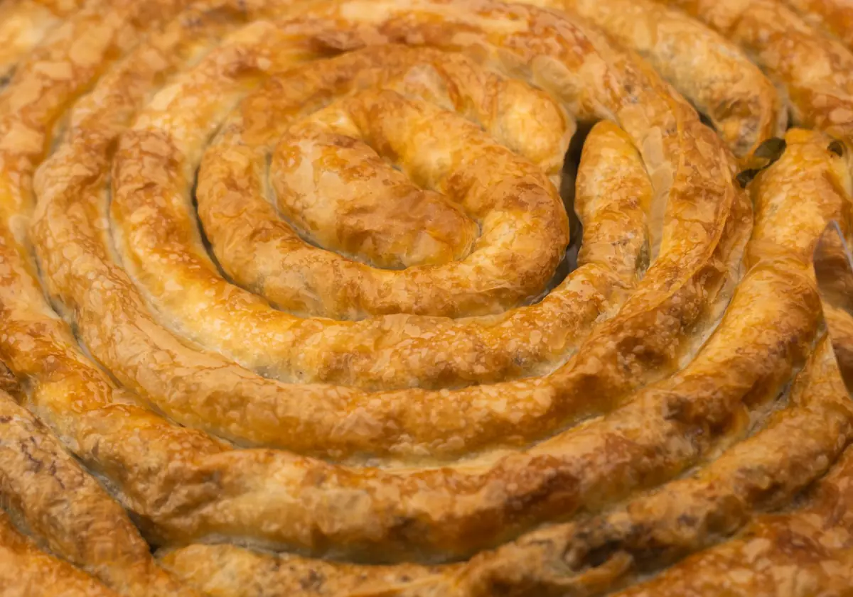 Golden brown spiral-shaped Turkish borek with flaky pastry texture, capturing delicious savory detail.