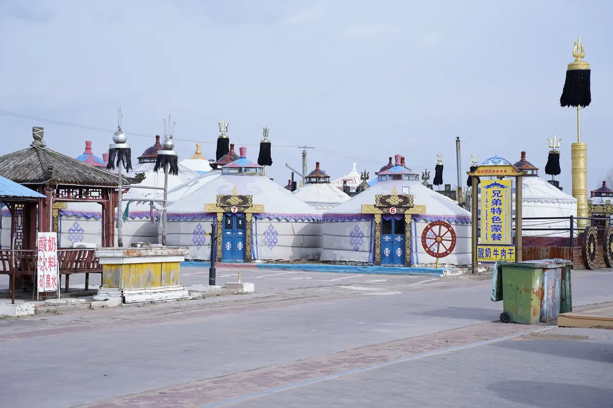 Colorful traditional Mongolian yurts in a cultural village under a clear blue sky.