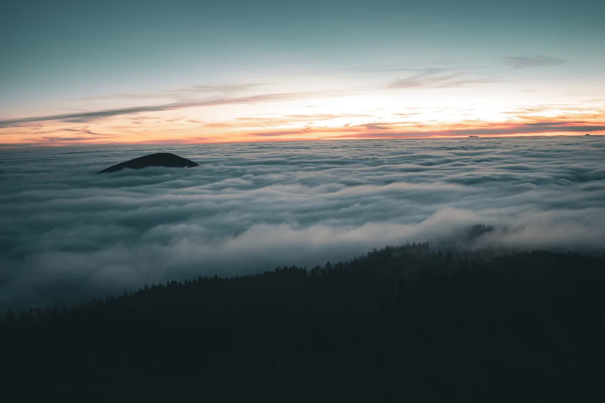 A captivating twilight view over Hvozd Mountain in Plzeňský kraj, with clouds and a hint of sunlight.
