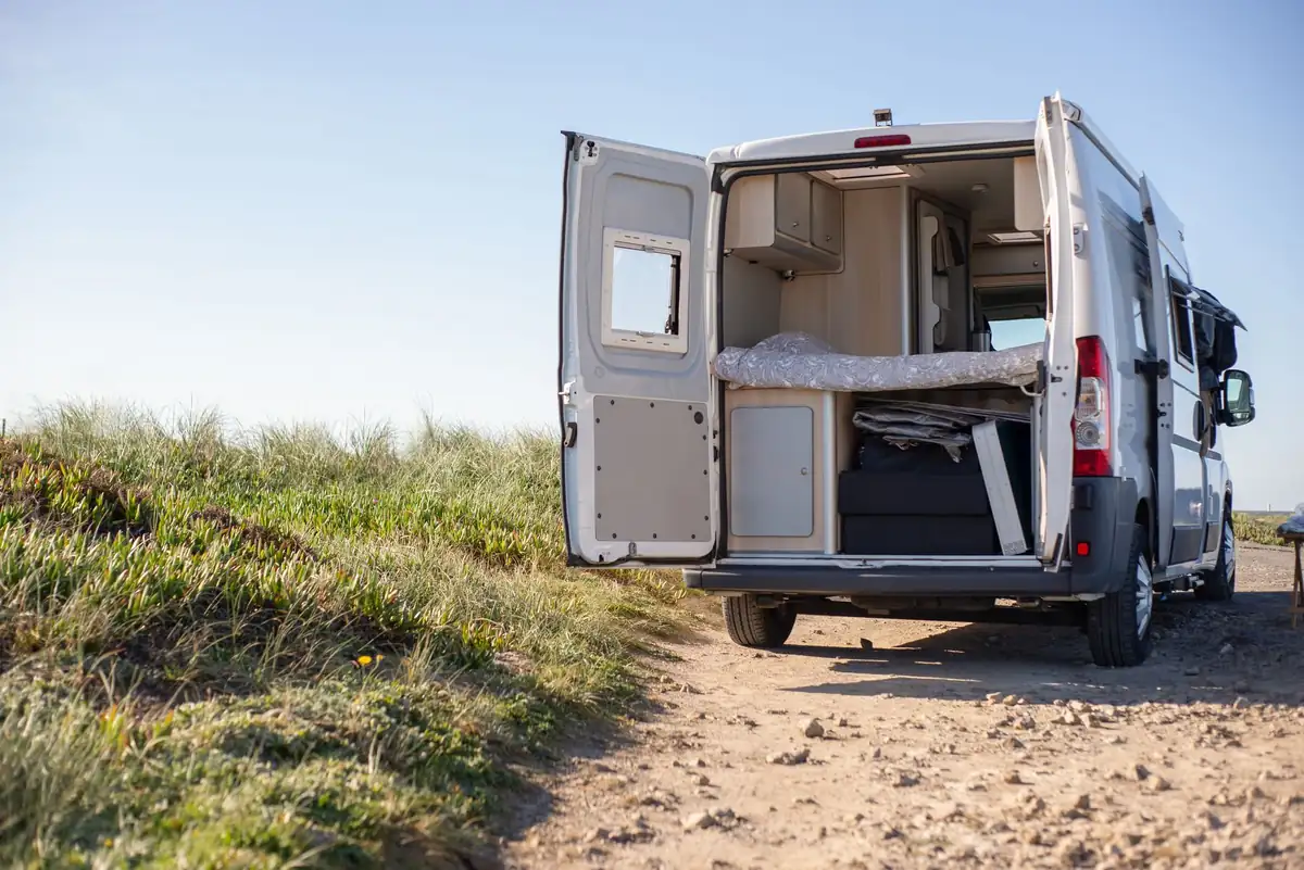 Open camper van on a sunny day, perfect for a rural getaway in nature.