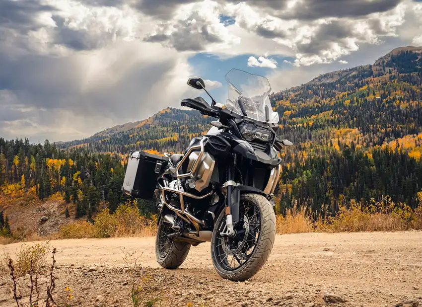 Powerful adventure motorcycle parked on a mountain road with autumn foliage.