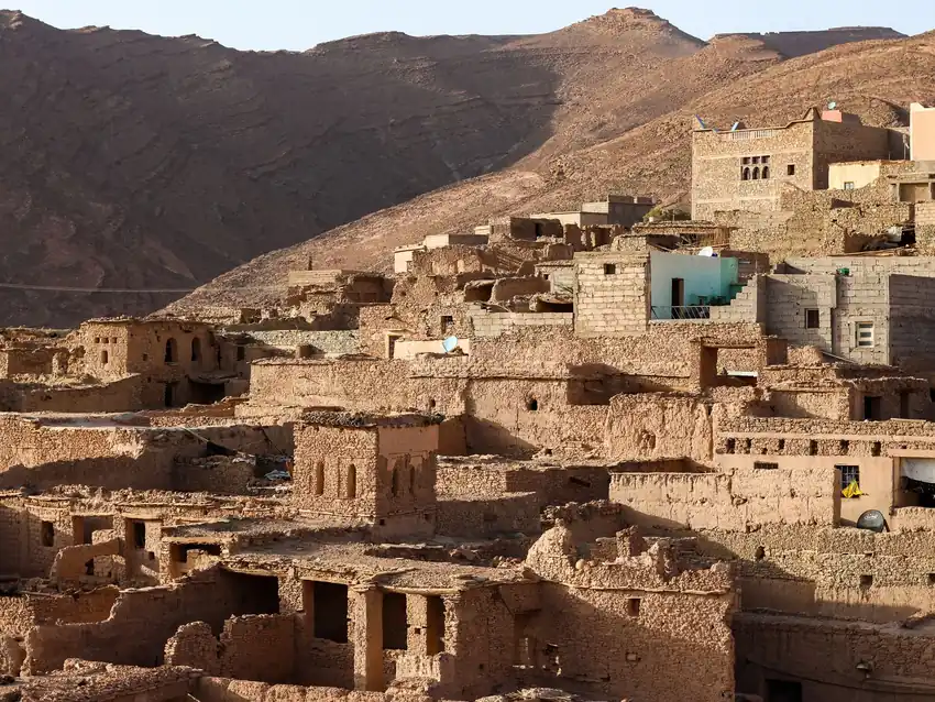 Capture of rustic adobe buildings in Tata, Morocco against mountainous backdrop.