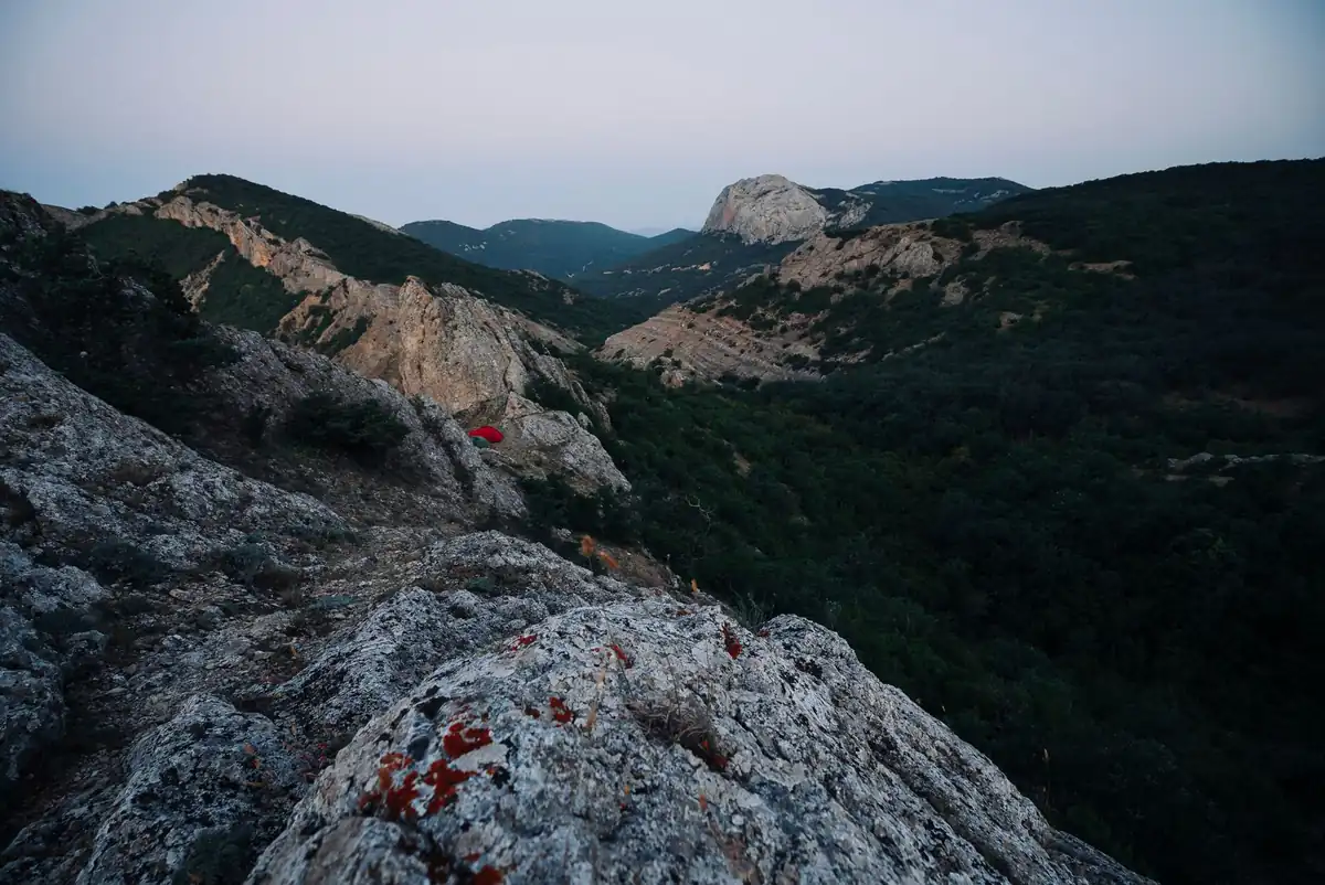 A breathtaking view of a mountain valley at dusk, showcasing rugged rock formations and lush greenery.